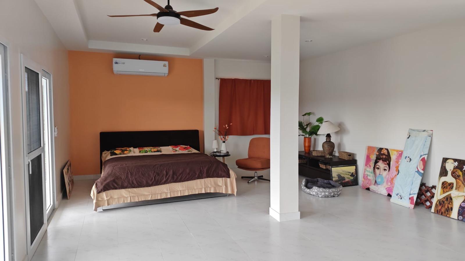 Furnished master bedroom with orange accent wall
