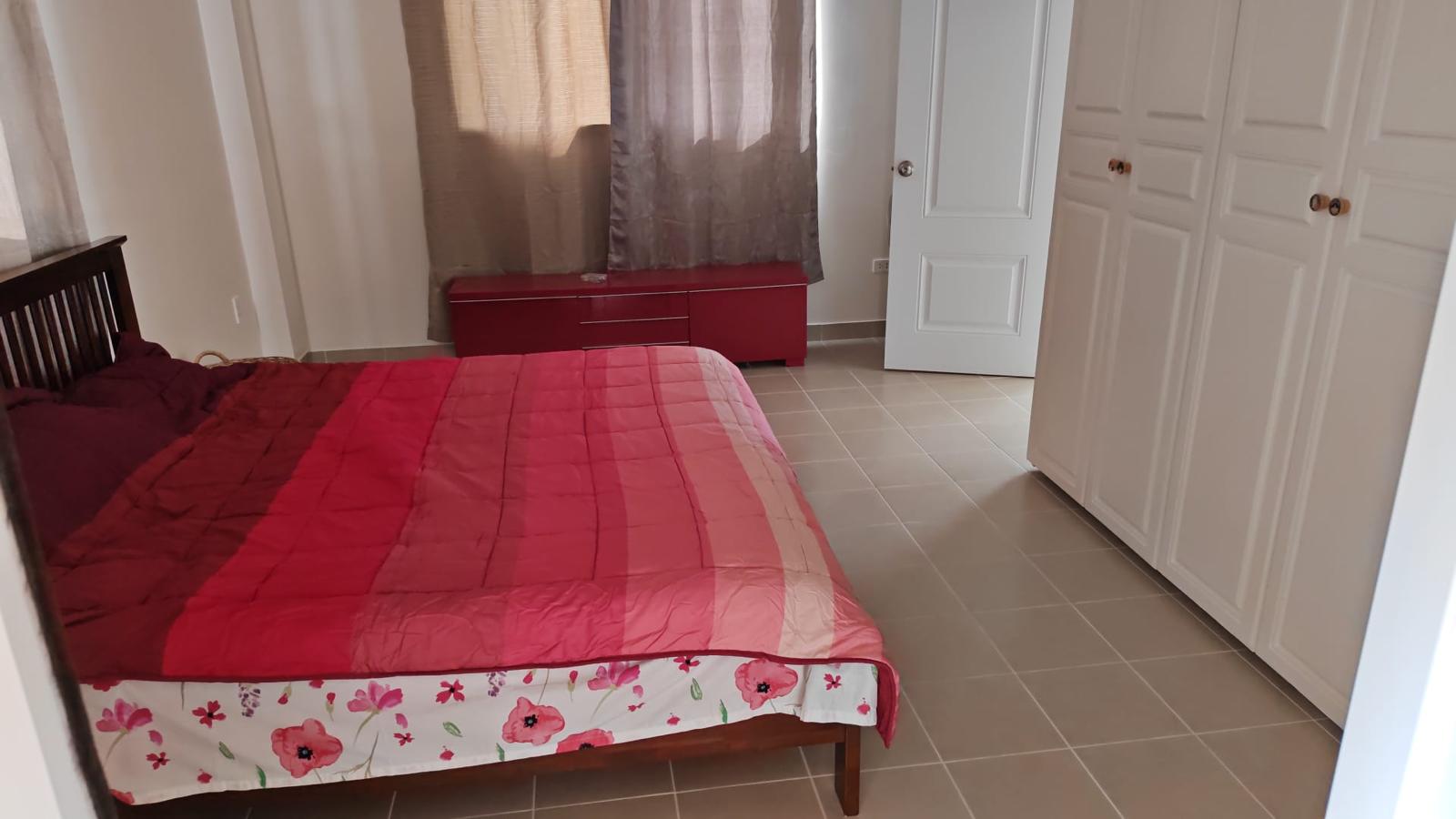 Furnished bedroom with red bedspread and wardrobe
