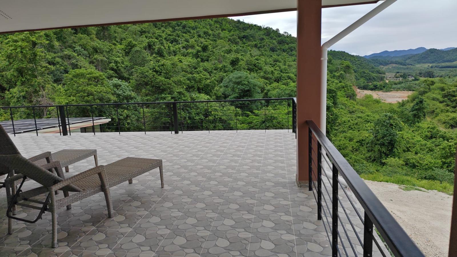 Furnished terrace with lounge chairs and forested hillside view